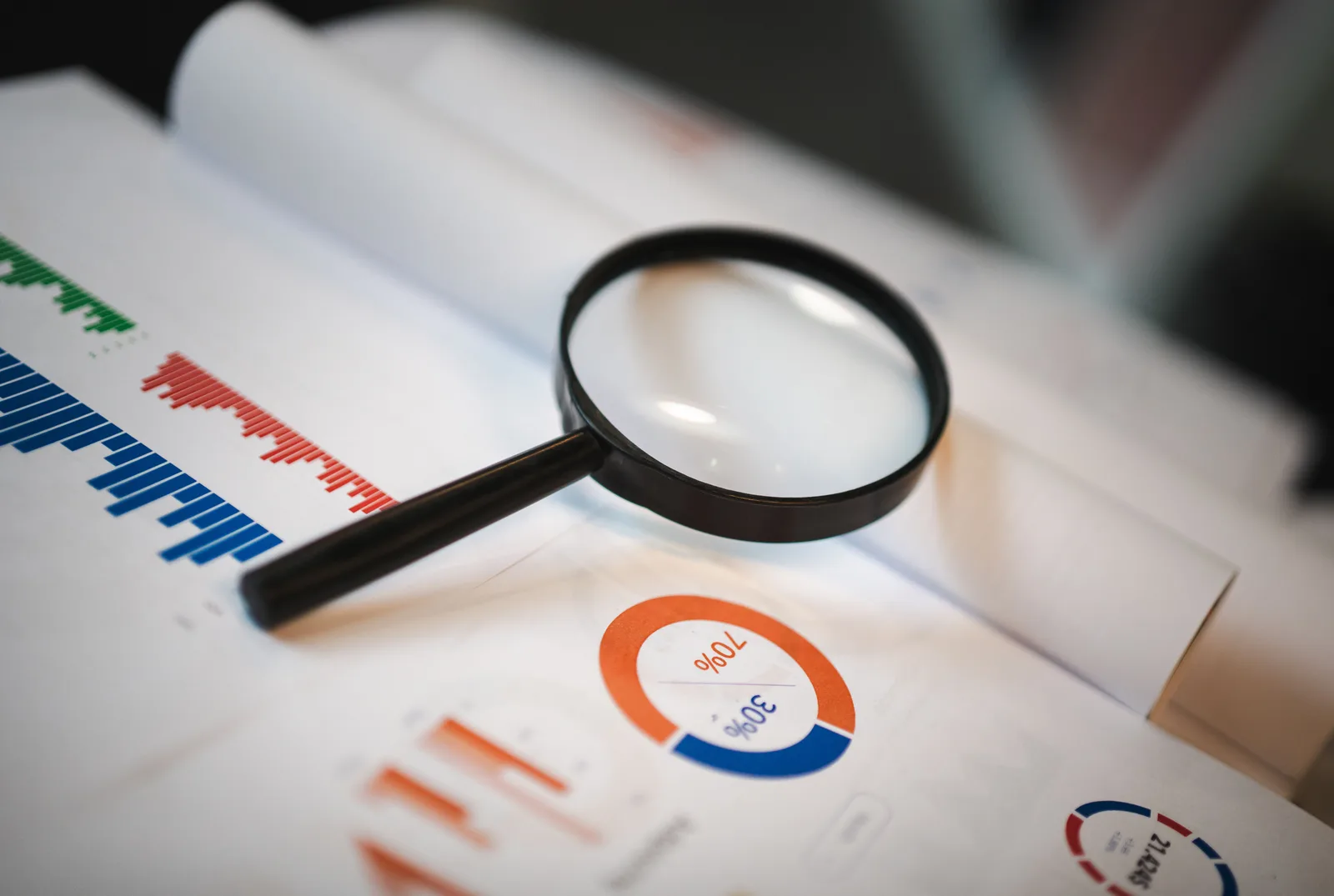 An image showcasing a magnifying glass placed on financial graphs and charts depicting statistical data. How to vet ecommerce conversion optimization case studies