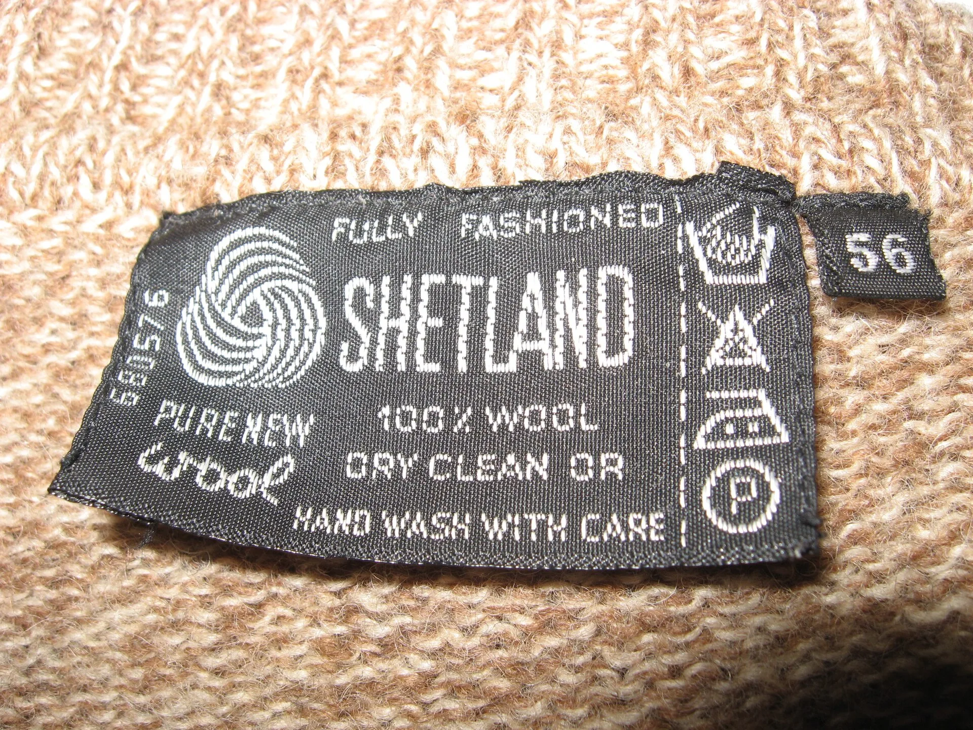 Label with care symbols on a wool sweater. Ecommerce Listing Language: Material Claims and Care Lines