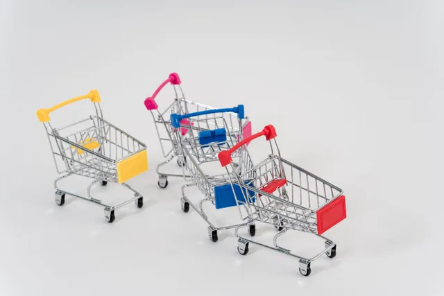 Three mini shopping carts with colorful handles and labels on a white background. Ecommerce marketing strategy mistakes hidden in the plan
