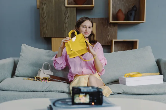 A young woman showcasing a yellow handbag during a live online fashion sale session. 3 parts of ecommerce marketing strategy trends, explained