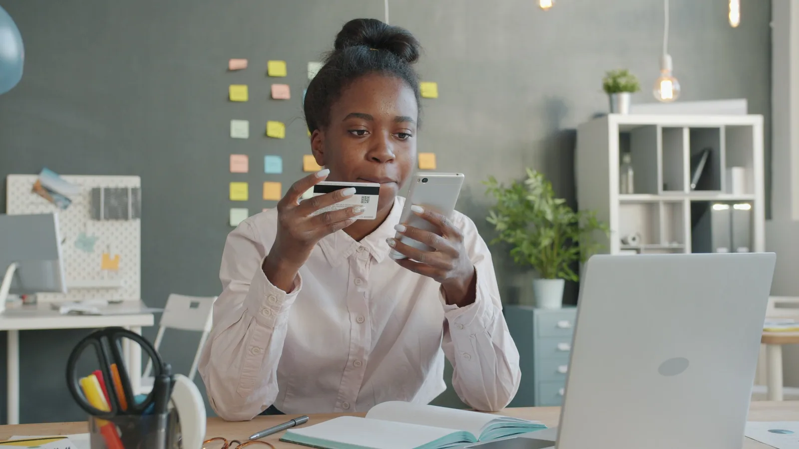 Young woman in office using credit card and smartphone for online shopping. How to evaluate ecommerce SEO trends