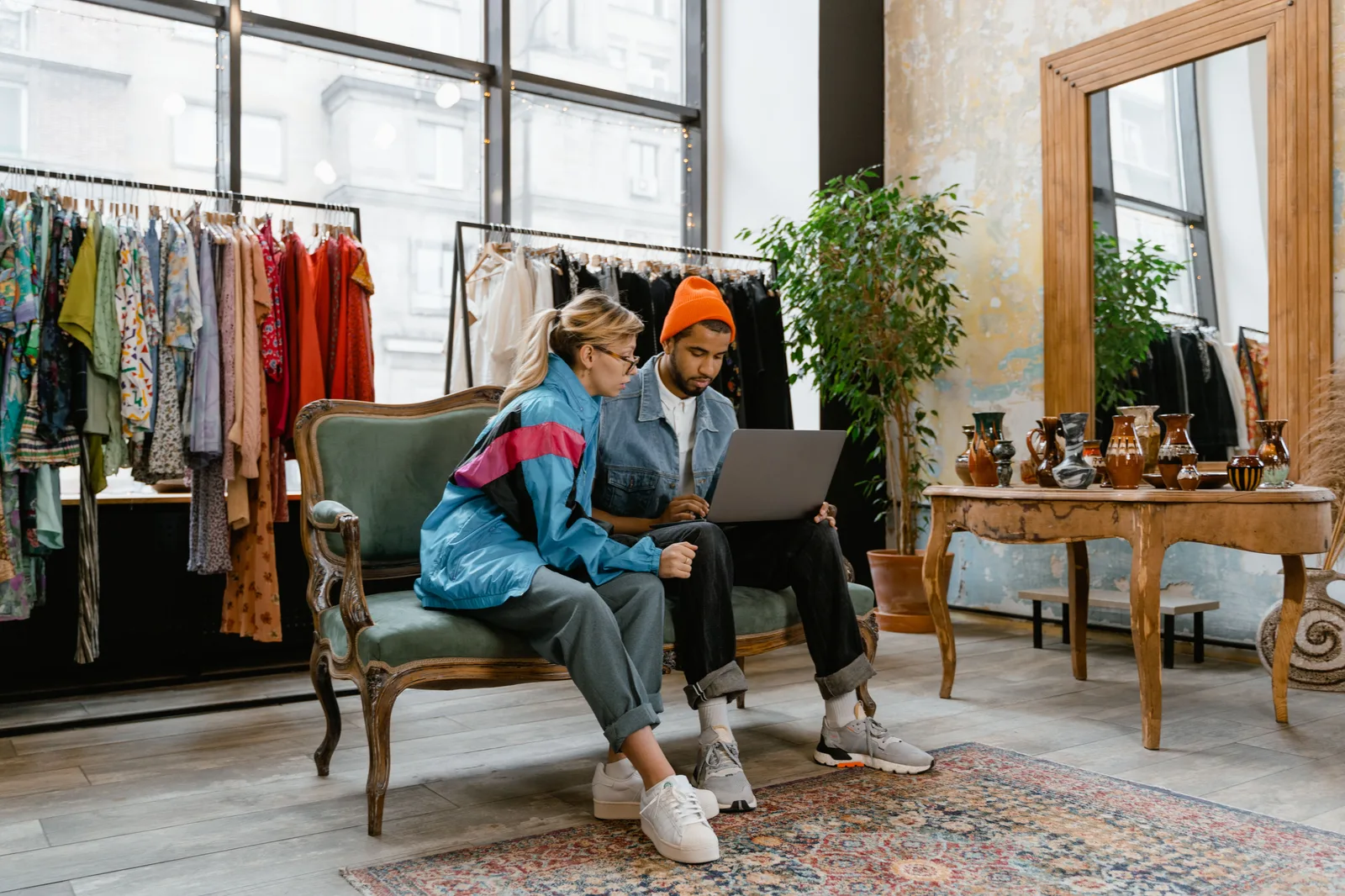Two individuals collaborating on a laptop in a fashionable boutique setting. How to improve ecommerce SEO with a focused business plan: the parts worth your time